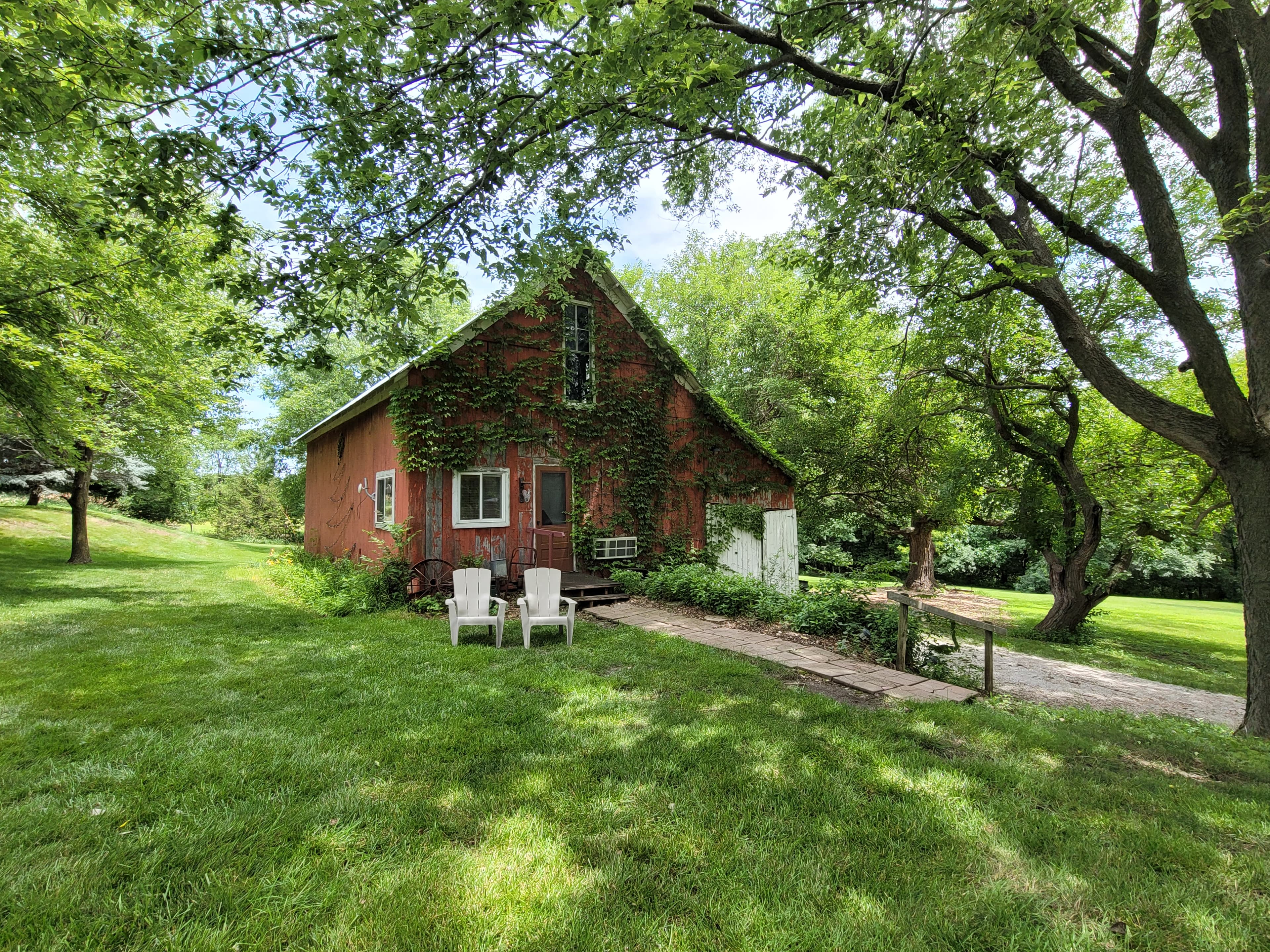 Exterior view of renovated horse barn surrounded by green grass and flourishing trees.