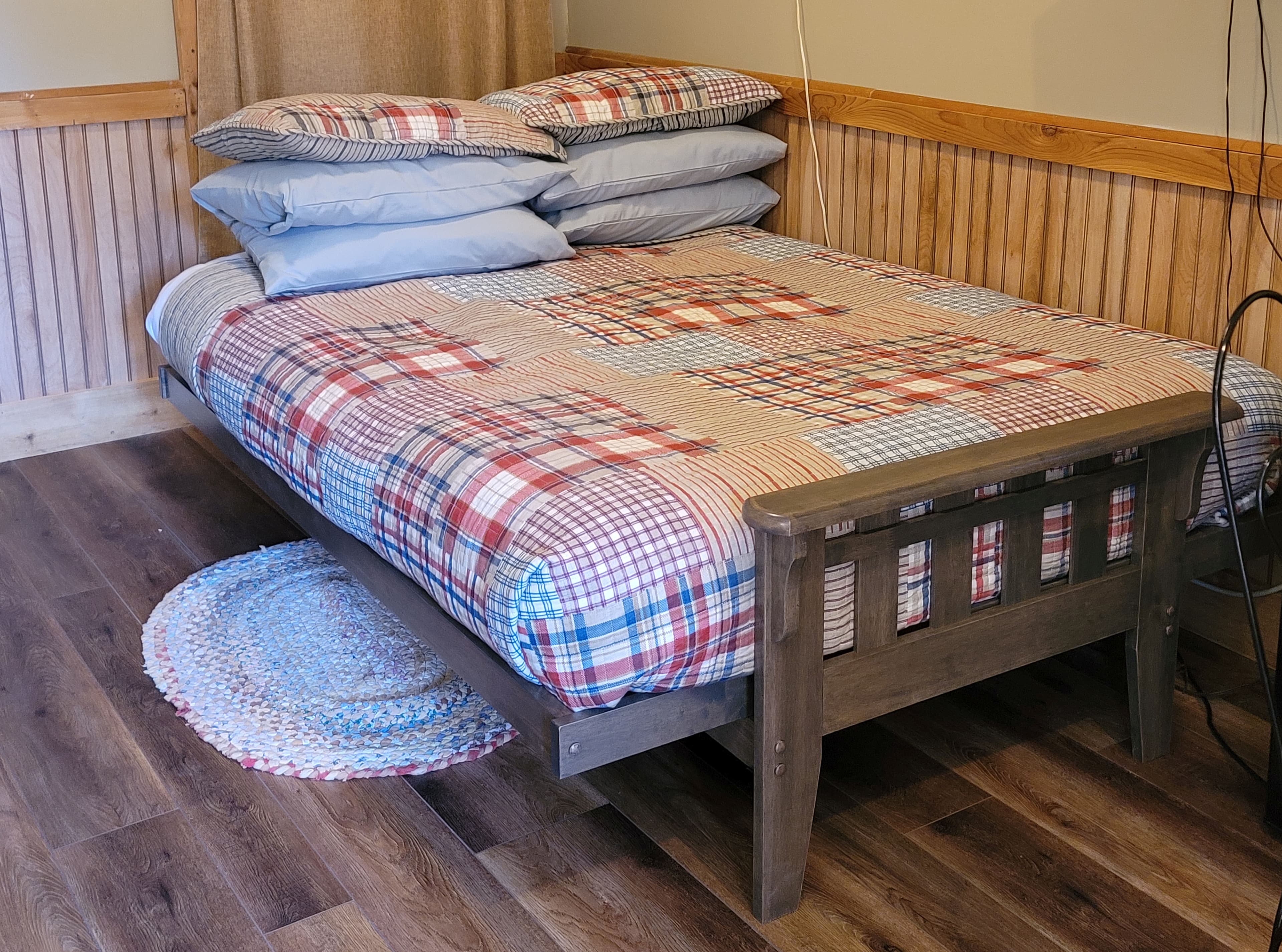 A sweet rustic wooden futon is made up for extra guests with cozy plaid quilted bedding