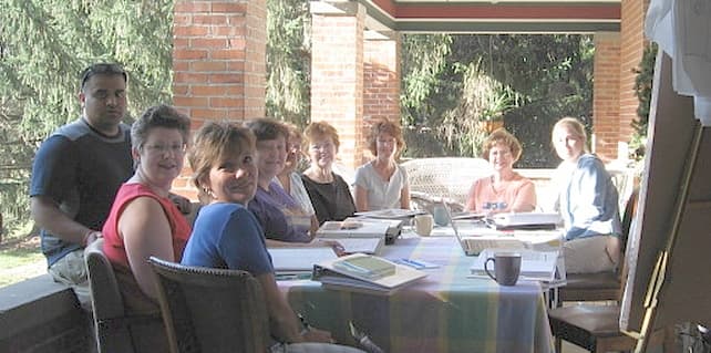 A group of people on a sunny day having a business meeting out on the porch