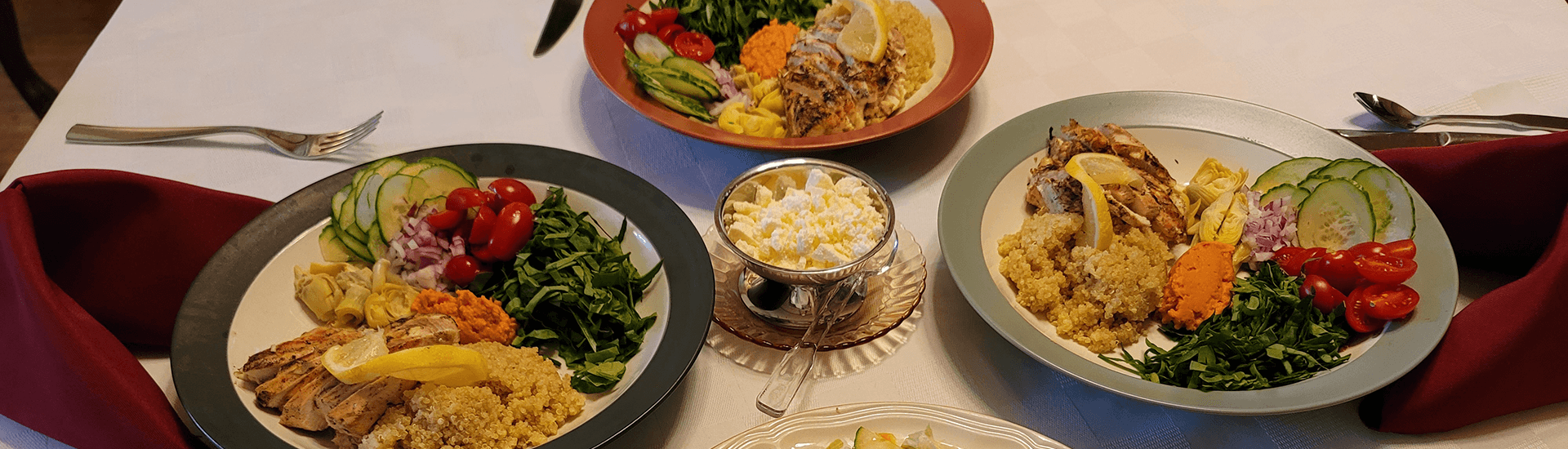 A table set with 3 plates with various dinner foods and salads.