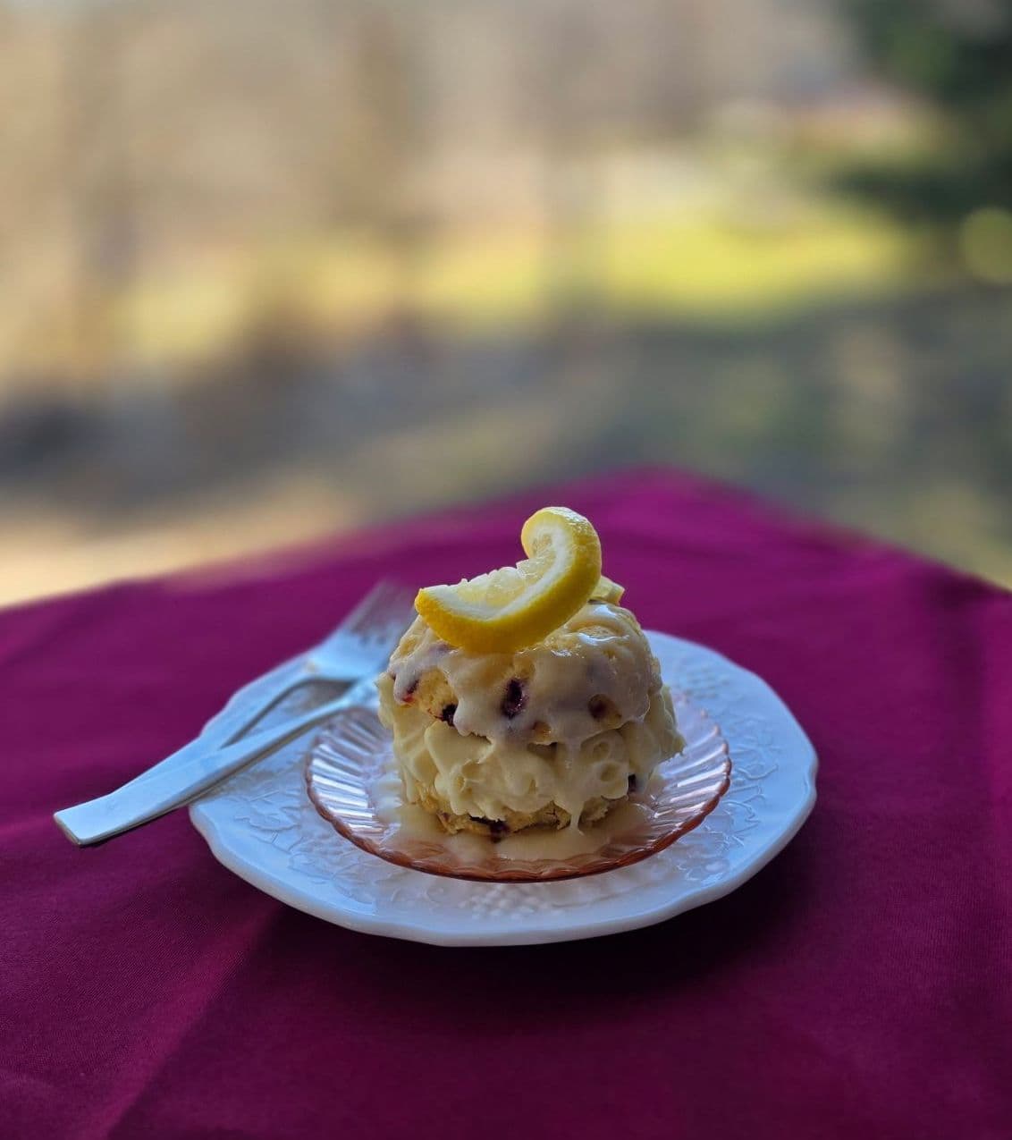 A lemony dessert served on a decorative plate, sitting on a pink tablecloth.