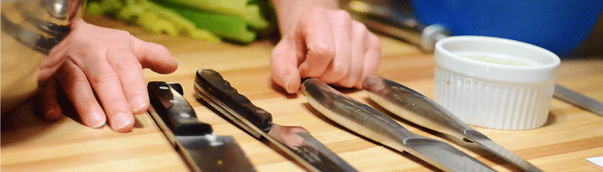 Hands on cutting board with multiple knives and prep bowl