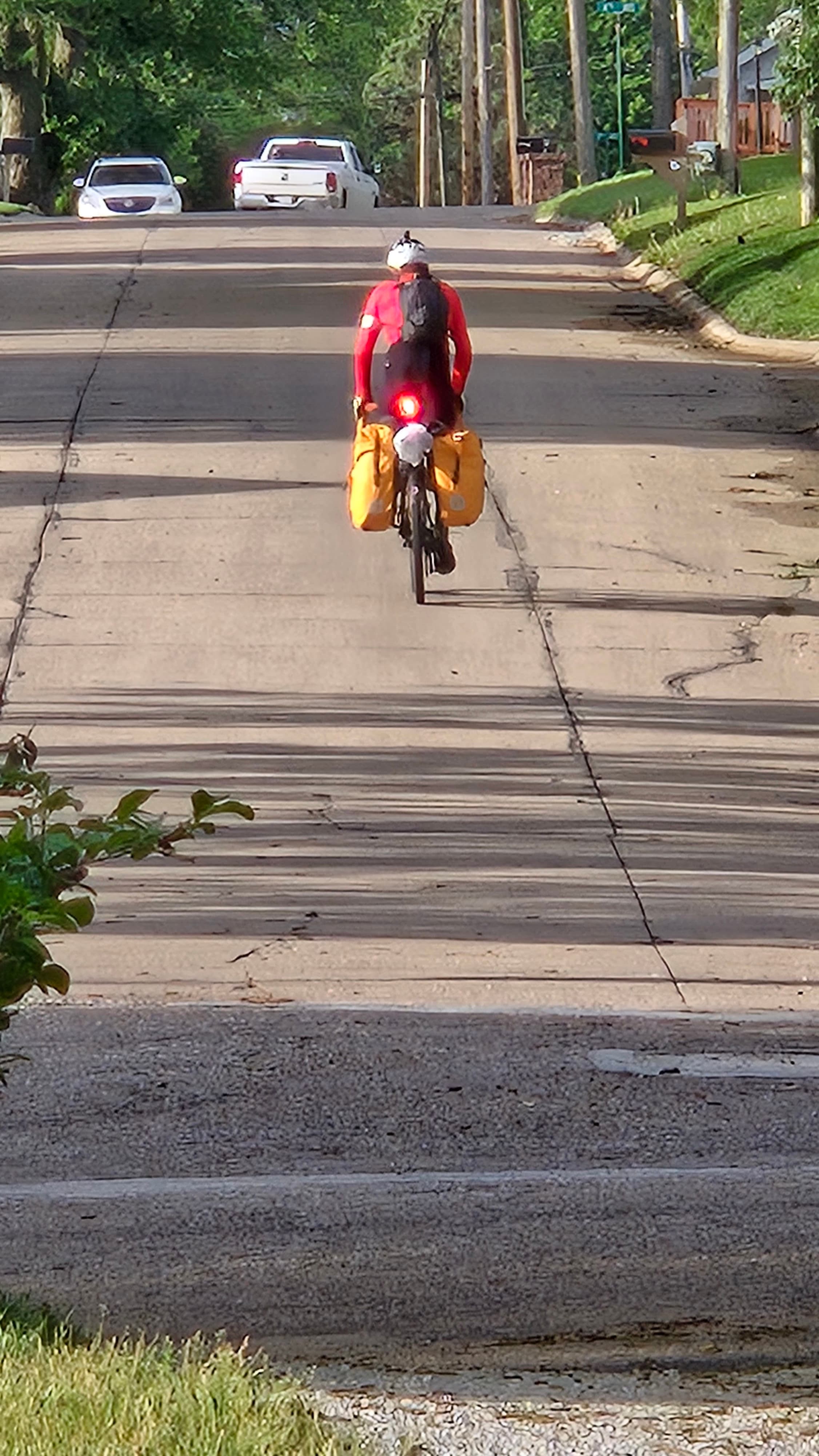 Cyclist Gary rides away from Whispering Pines Bed & Breakfast with a loaded touring bicycle after a rest day in Nebraska City.