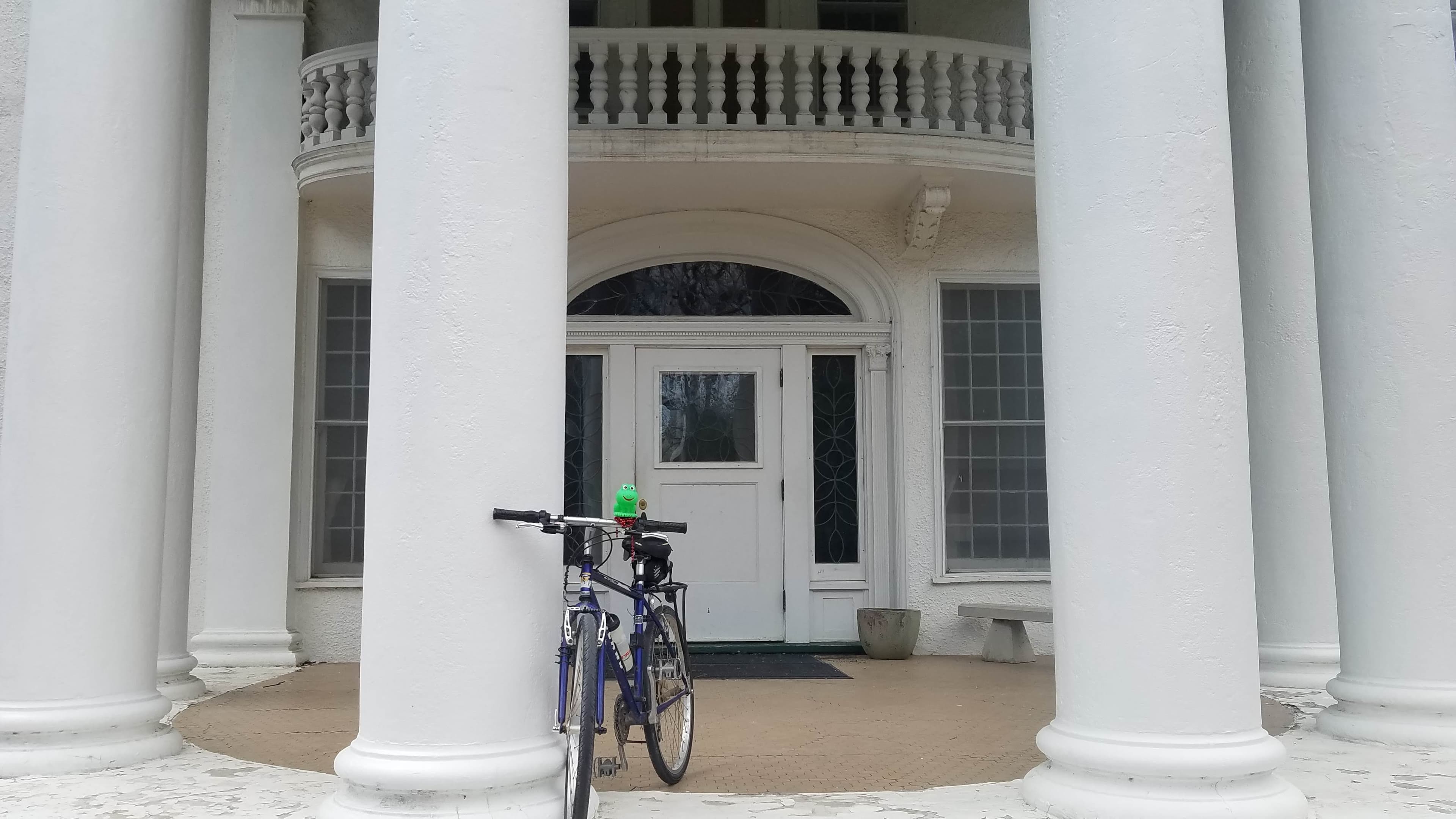 A bicycle leans against the columns of a historic Arbor Lodge Mansion
