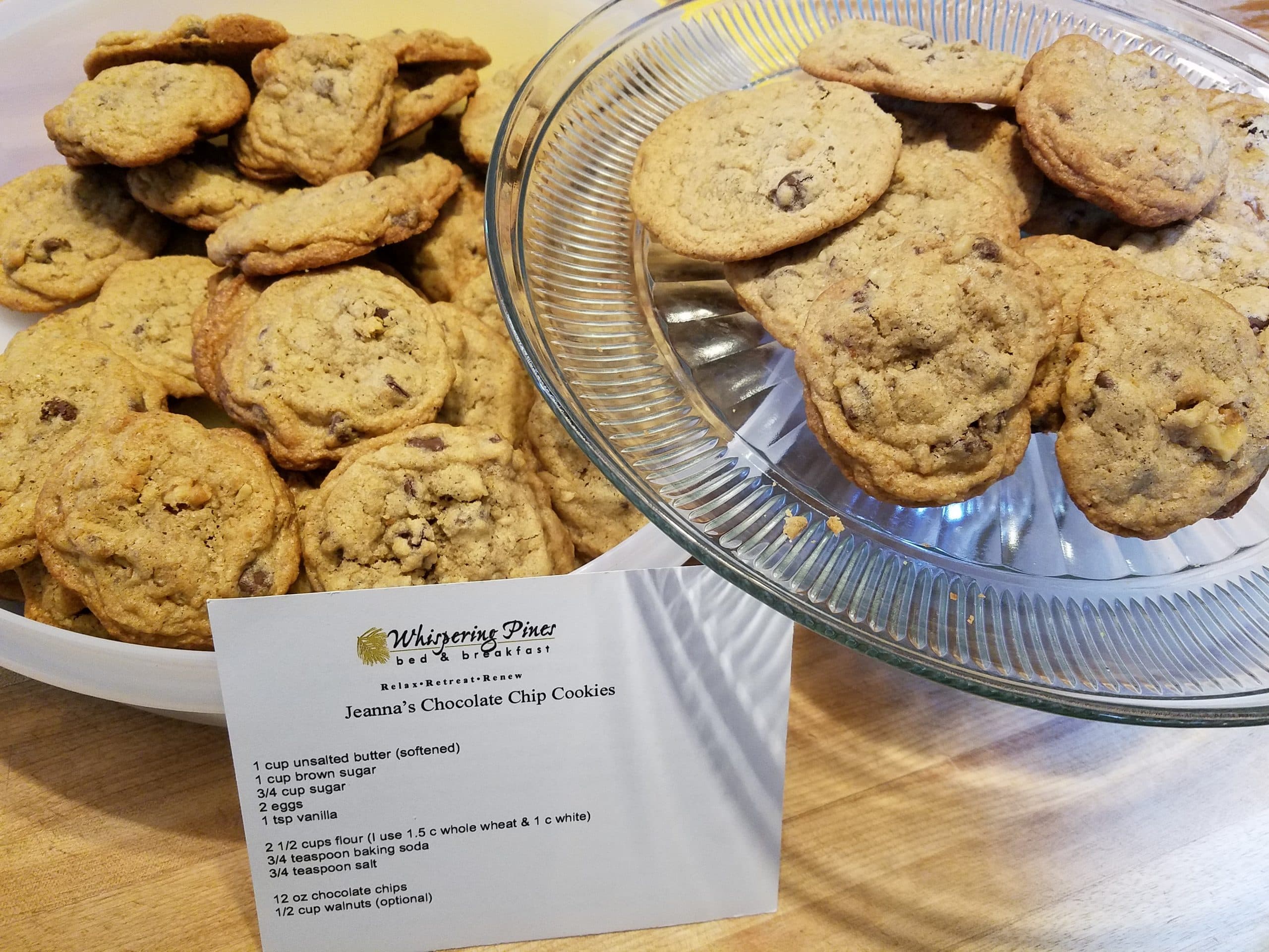 A plate and a bowl filled with chocolate chip cookies alongside a recipe card for Jeanna's Chocolate Chip Cookies. A plate and a bowl filled with chocolate chip cookies alongside a recipe card for Jeanna's Chocolate Chip Cookies.
