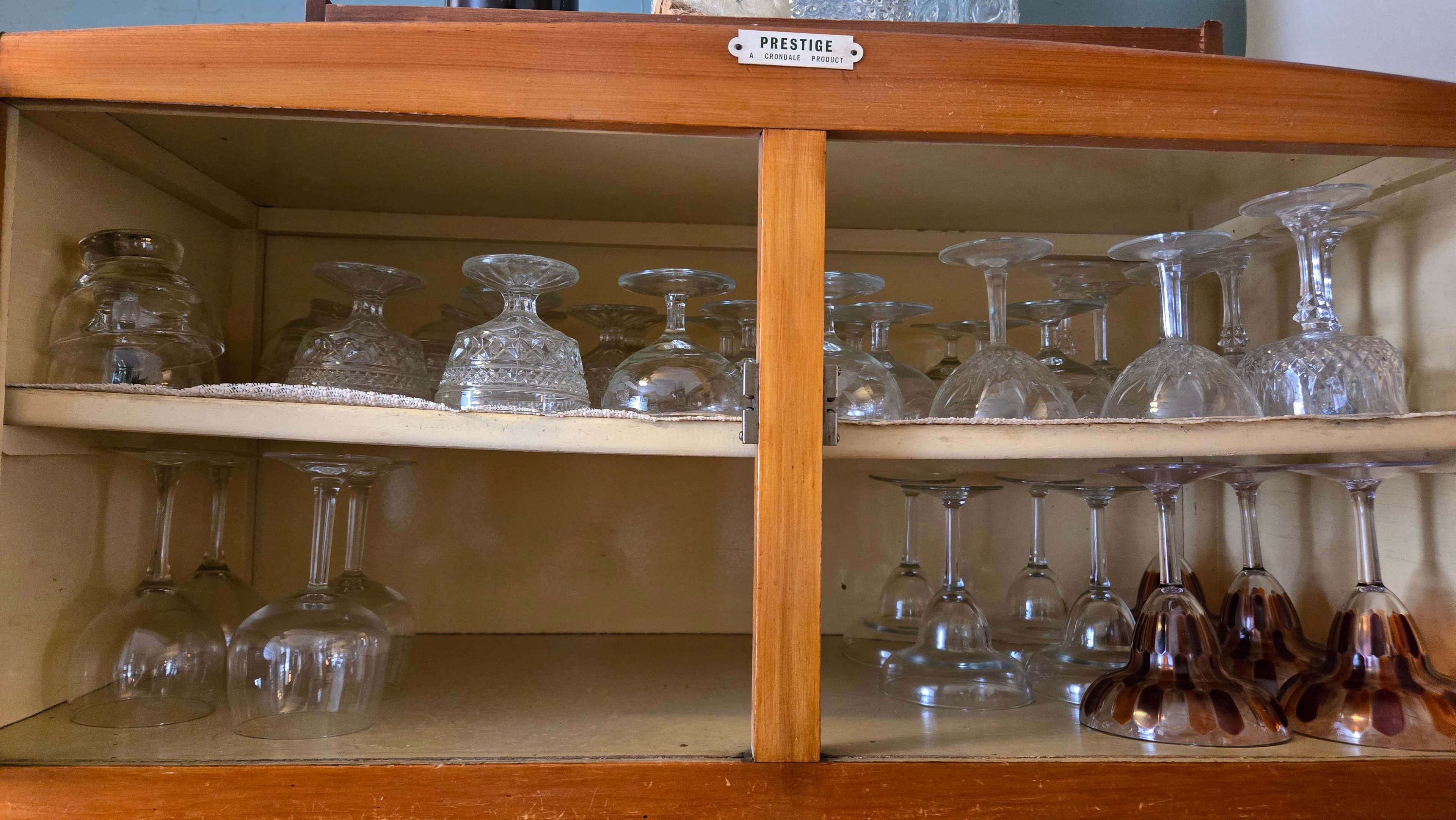 A wooden cabinet showcasing neatly arranged glassware.