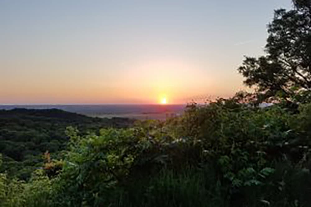 A serene sunset over lush green hills.