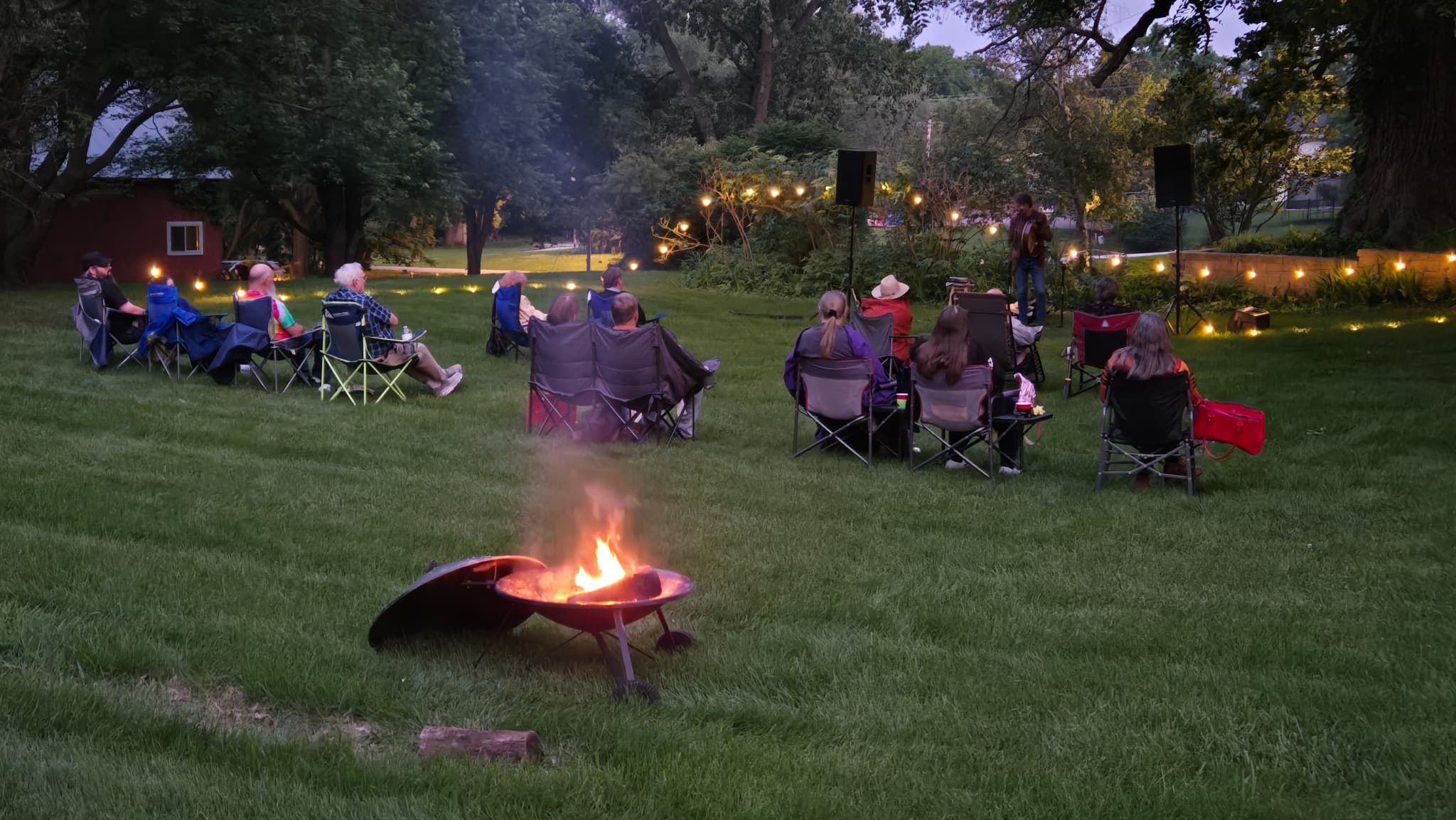 Guests relax under the Burr Oak tree during an outdoor John Byrne concert at Whispering Pines Bed & Breakfast in Nebraska City.