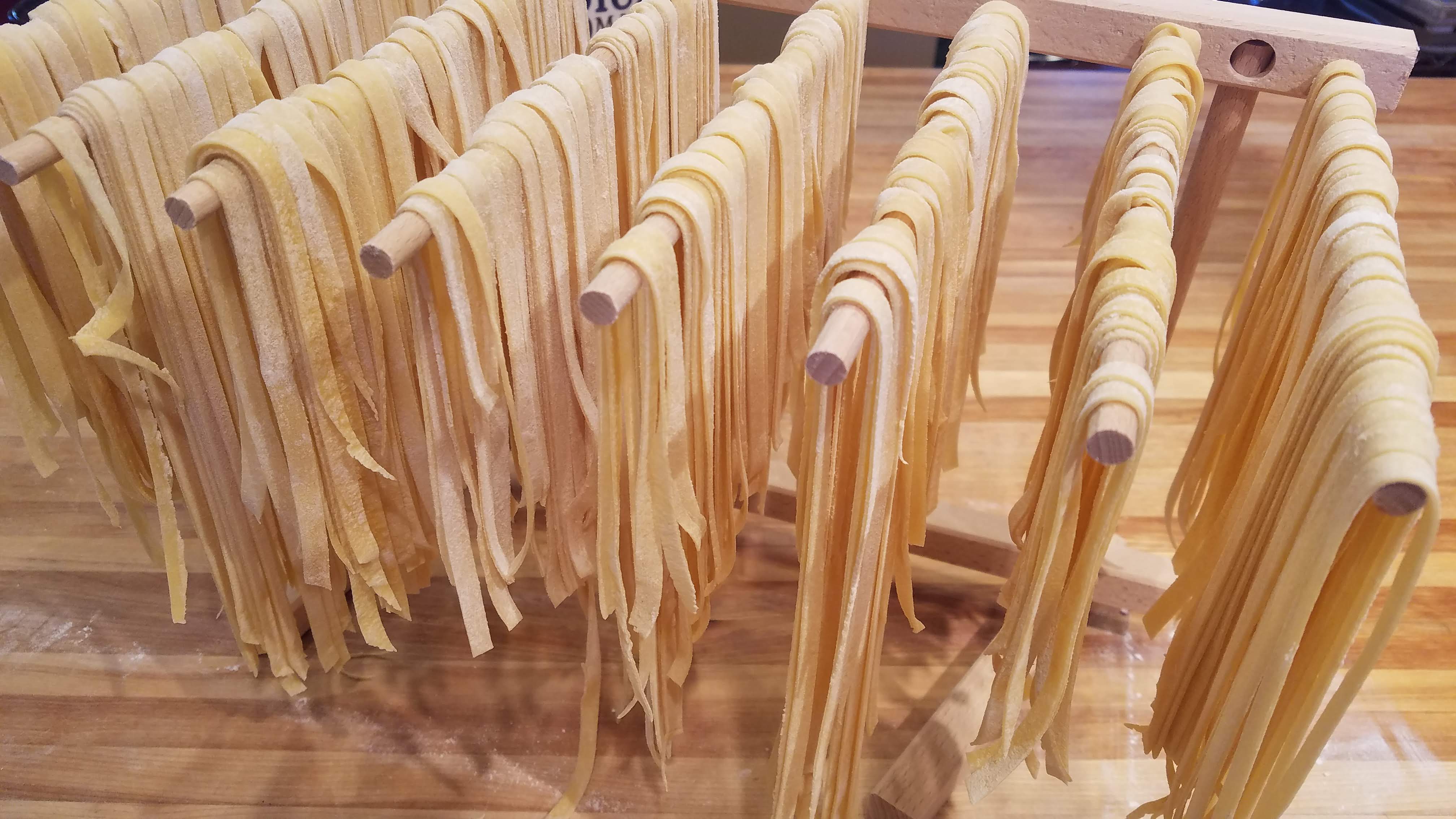 Freshly made pasta hanging to dry on a rack.
