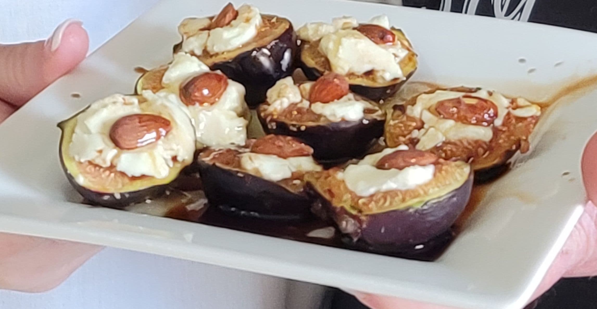A plate of stuffed figs topped with cream and almonds.