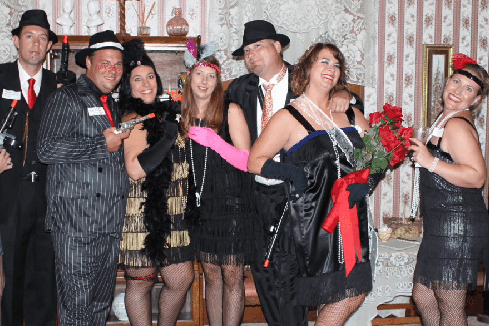 A group of people dressed in 1920s-style outfits pose together for a photo.