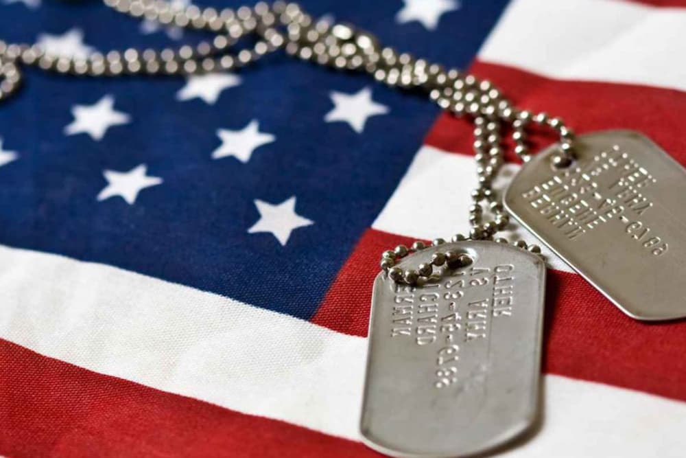A close-up of military dog tags lying on an American flag.