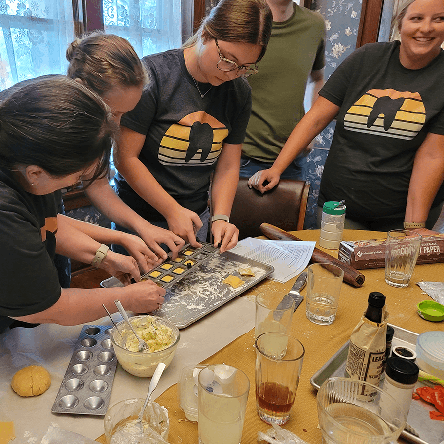 A group of people is preparing dough and using a baking tray in a kitchen.