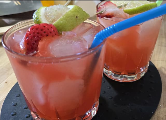 2 cranberry cocktails with lime garnish and straw