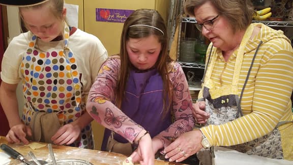 Grandmother and granddaughters making pasta together during a cooking class at Whispering Pines.
