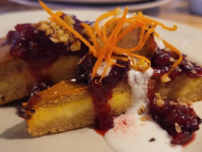 (French) Baked Pancake topped with blueberry sauce, yogurt drizzle nuts and orange zest on a plate