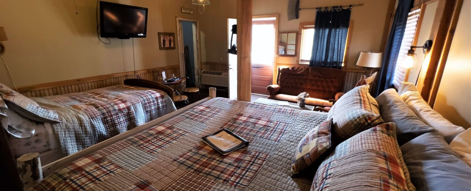 Barn Room showing King bed and Double bed with TV on wall and Ice Cream parlor table and chairs.